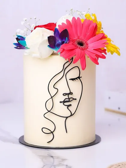 We celebrate the beauty of femininity with this modern line art cake. A minimalist silhouette of a woman's face is drawn on a pristine white canvas, crowned with a vibrant bouquet of fresh, colorful flowers, creating a cake that is both art and dessert.