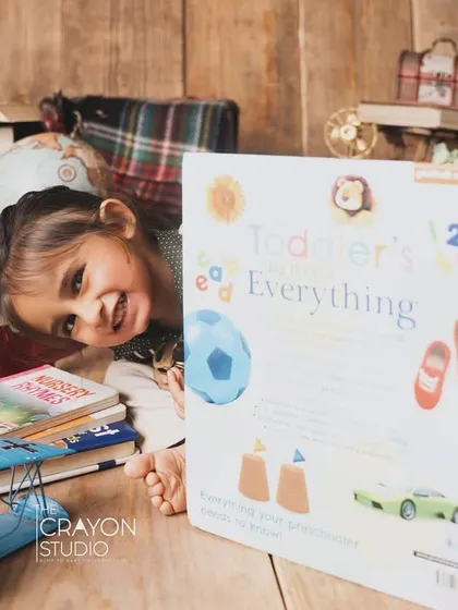 Peek-a-boo. A playful moment during the scholar-themed shoot, with the toddler hiding behind a giant book.