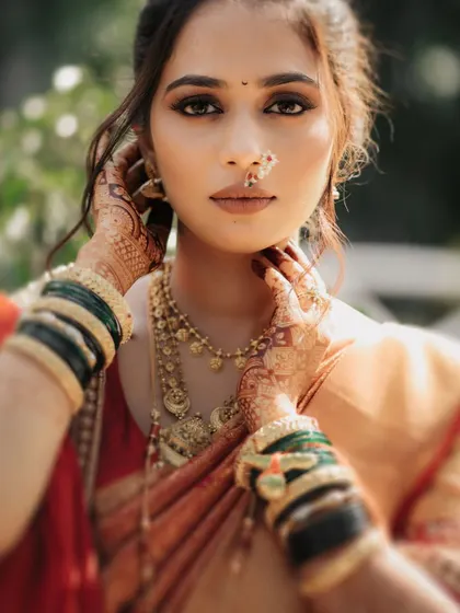 A stunning close-up beauty shot of the bride, highlighting her makeup and traditional Maharashtrian jewelry.