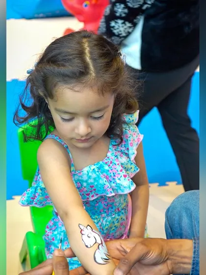 Getting a temporary tattoo is always a party highlight. This little guest is getting a unicorn tattoo, adding a touch of magic to her mermaid party experience.