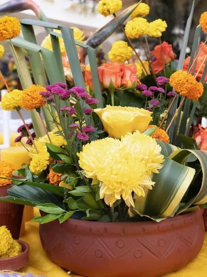 A detailed shot of the floral centerpiece, combining traditional marigolds with roses and other flowers in an earthen pot for a rustic touch.