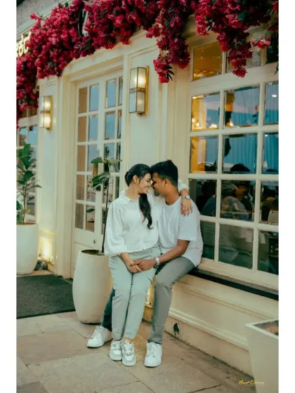 A couple shares a quiet moment sitting on a windowsill of a charming cafe. The bougainvillea flowers add a splash of color and romance to this urban shot.
