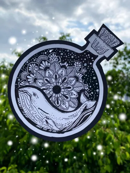 A magical piece featuring a whale and a floral mandala inside a bottle. This black and white ink illustration was cut out and photographed against a natural background to enhance its enchanting feel.