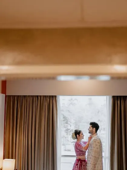 An artistic shot, framing the couple in a doorway as they stand by a window, creating a sense of intimacy and a peek into their world.