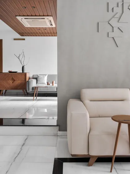 **Achrome, Ahmedabad:** The design layers different spaces, offering glimpses from one area to another. The wooden ceiling detail and carefully selected furniture create a warm and inviting atmosphere within the minimalist, achromatic palette.