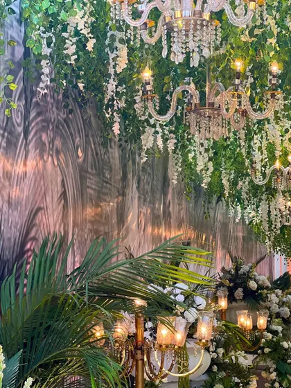 A close-up of the decor, showing the rich textures of the tropical foliage and the elegant chandeliers, creating a beautiful play of light and shadow.