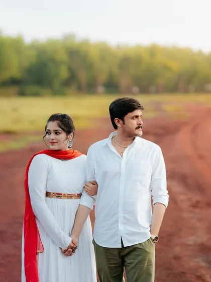 A quiet moment of togetherness on a country road. This shot captures the couple walking hand-in-hand, symbolizing the start of their journey together against a backdrop of lush greenery.