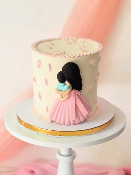 A simple, elegant cake celebrating motherhood. This design features a fondant silhouette of a mother holding her child.