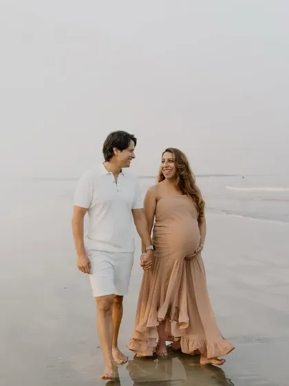 A beautiful, windswept moment on the beach. The flowing dress and the soft light create a truly romantic and dreamy maternity portrait.
