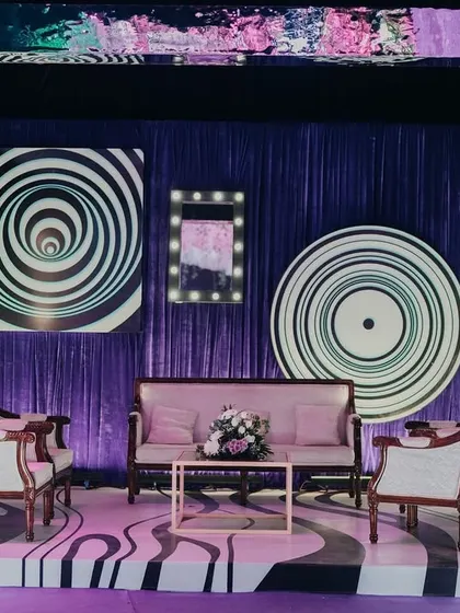 A unique photo booth designed with hypnotic spiral patterns and a purple-draped background. The vintage-style furniture provides a cool contrast to the modern, psychedelic visuals.