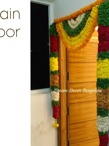 Main door decoration for a housewarming, using colorful flower garlands. This traditional 'chand hoova' decor adds a festive and auspicious touch to the new home.