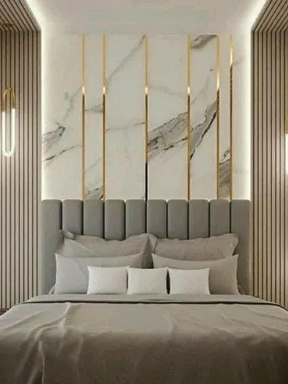 In this design, we combined vertical wood slats with marble panels and gold-finished inlays for a highly luxurious accent wall. The simple grey bedding and hanging lights keep the focus on the intricate wall details.