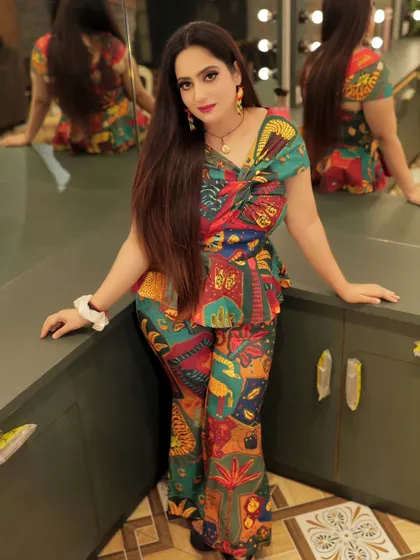 A full-length shot from the same series, showing the complete two-piece outfit. The model's confident pose against the vanity mirrors creates a chic, modern vibe.