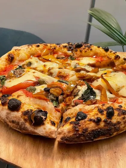 A pizza fresh from "Akasha's Lab". This one is topped with mushrooms, peppers, and spinach, showcasing the beautiful char and puffy cornicione.