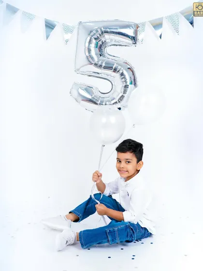 Holding a big number "5" balloon, this birthday boy is ready to celebrate his special day.