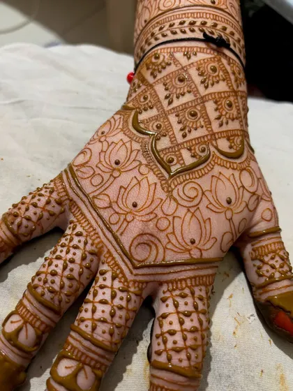 The fresh application of Chaitra's wedding mehendi, showing the intricate lotus grid pattern on the back of her hand.