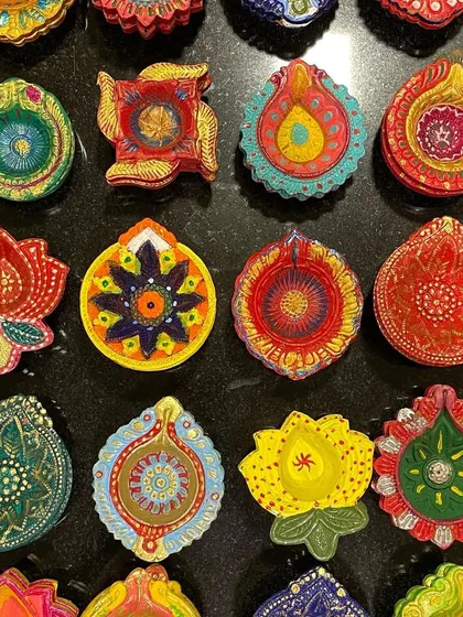 A vibrant collection of hand-painted diyas ready to be packed into my Diwali hampers. The variety of colors and patterns ensures every gift box is special.