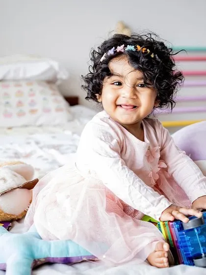 This little girl's smile is infectious as she plays with her favorite toys. Toddler sessions are all about capturing their budding personality and gorgeous curly hair.