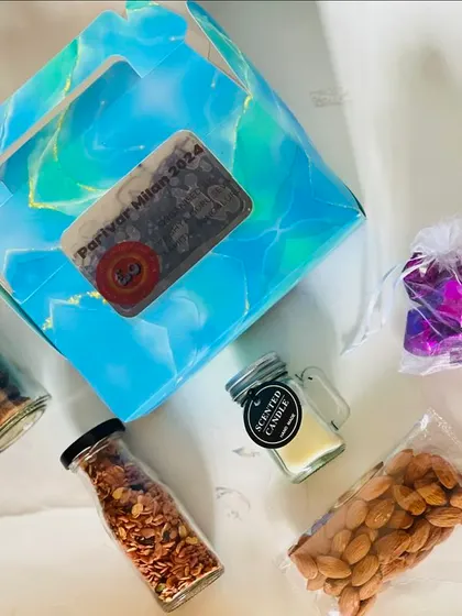 The contents of one of the favor boxes displayed. It includes a scented candle, almonds, and other small treats, making for a thoughtful thank you gift.