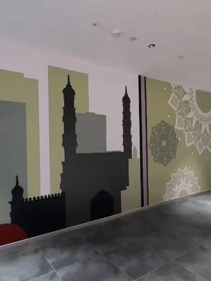 This mural in the Providence office features an abstract, multimedia design themed on Hyderabad. It combines silhouettes of city landmarks with modern graphic elements and mandala patterns.
