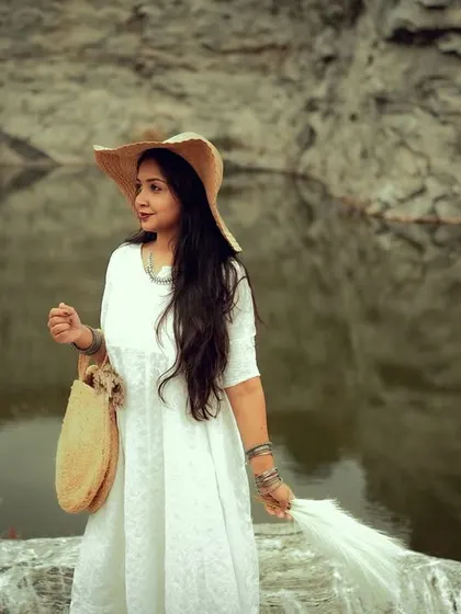 A fashion-forward portrait of a woman in a flowing white dress against a dramatic rock and water backdrop. This image is perfect for a portfolio that aims to blend style with nature.