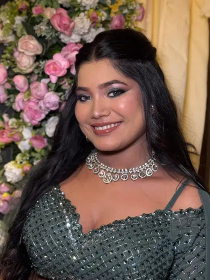 A happy client photo against a floral backdrop. The dramatic eye makeup stands out while the rest of the look remains fresh and glowing.