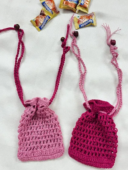 These two handmade crochet pouches in shades of pink are perfect for gifting or can be used as a soap saver. They are shown here with small chocolates to give an idea of their size.
