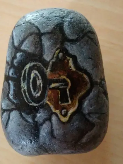 A small piece of pebble art showing a vintage keyhole on a cracked stone wall. I used acrylic paints to create this illusion of texture and mystery on a smooth stone.