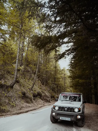 Photos of Suzuki Jimny and Ford Endeavour vehicles driving through dense pine forests and on open roads. These images showcase the capability of these vehicles in tough terrains.