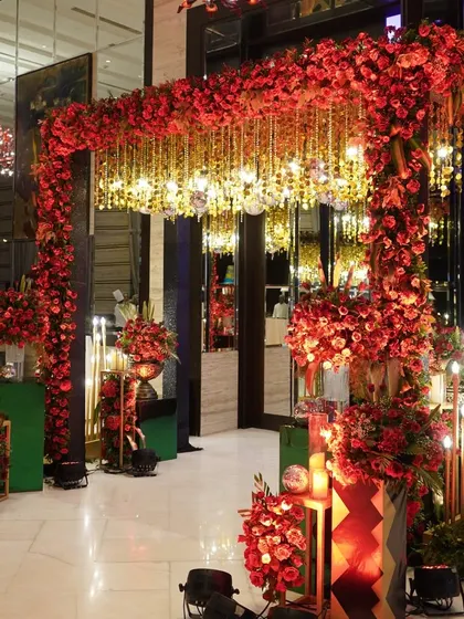 This entrance is all about passion and glamour. A massive arch of red roses is paired with a ceiling of hanging golden crystals, creating a luxurious and dazzling welcome for a cocktail and ring ceremony.