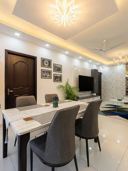 The dining area of the Bangalore home, adjacent to the living room, features a modern table, grey chairs, and a statement mirror wall.