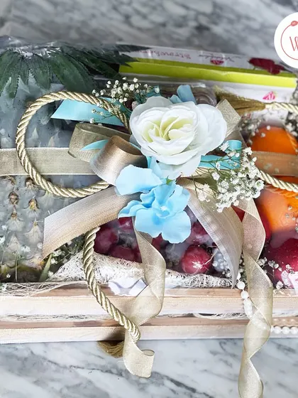 A beautiful hamper featuring fresh fruits like pineapple and grapes, elegantly wrapped and presented in a rustic wooden crate. A healthy and refreshing gift for any celebration.