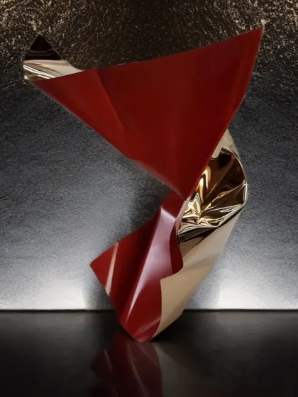 A twisting tabletop sculpture in red and gold from the Meteor collection. Its simple, fluid form makes a bold yet elegant statement on any surface.