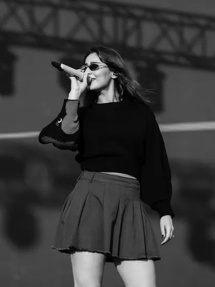 A cool, black and white shot from a sound check. The pleated skirt and sweater combo is a comfortable yet chic choice for rehearsals.