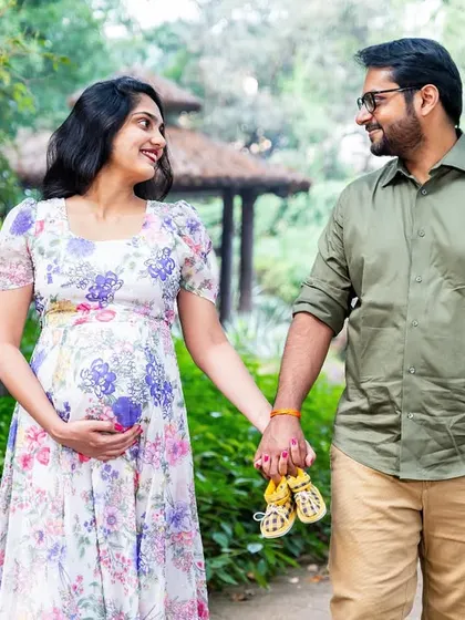 A beautiful, casual portrait of an expecting couple enjoying a walk in the park. The floral dress and the soft natural light give this photo a light and airy feel.