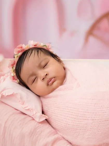 An even tighter shot focusing on the baby's serene expression. The soft pink tones and textures create a warm and gentle portrait.