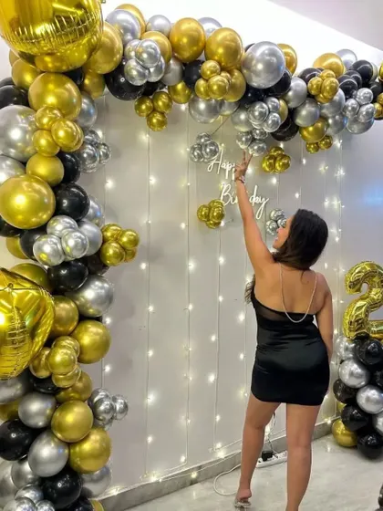 A classic and elegant birthday setup in black, gold, and silver. The balloon arch against a fairy light curtain creates a beautiful and affordable backdrop for any at-home celebration.