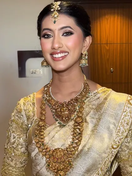 This bride's look is all about classic elegance. Her off-white Kanchivaram saree is paired with a custom gold embroidered blouse and traditional temple jewelry.