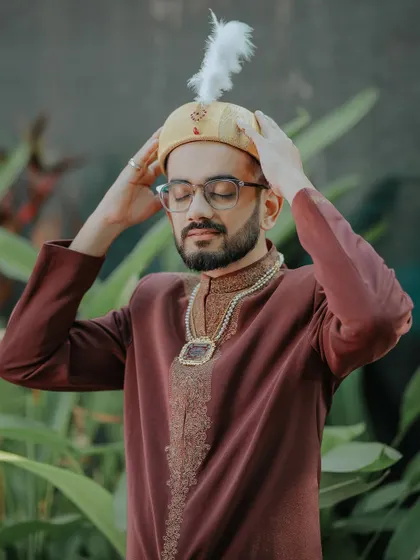 The groom, Murtaza, adjusts his traditional headwear, a moment of quiet preparation before the Nikah ceremony.