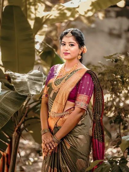 A beautiful bride stands in a lush garden, her traditional saree and jewelry perfectly complemented by the natural setting.