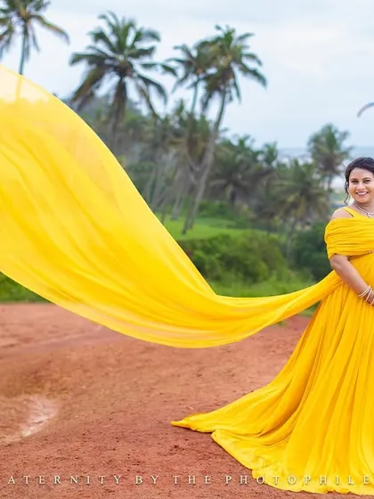 The vibrant yellow gown flows in the wind on the Varkala cliffs, with a paraglider in the background adding a touch of adventure to the scene.
