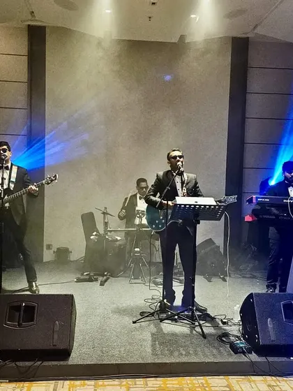 The band on stage under the lights at a corporate event. This shot captures the professional setup and concert-like feel of our performances.