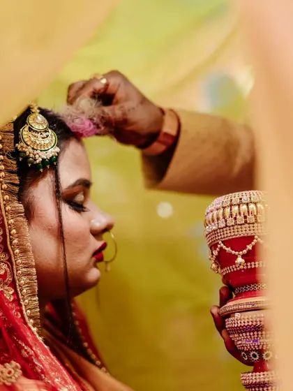 A clear, emotional shot of the Sindoor Daan ritual. This image documents the tradition with a focus on the bride's serene acceptance and the cultural significance of the moment.