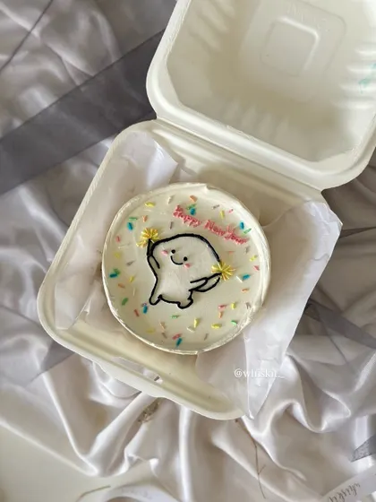 A cheerful "Happy New Year" bento cake with a cute, sparkling character. It's a festive way to ring in the new year with a personal-sized treat.