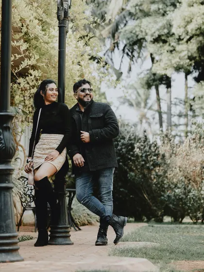 A relaxed and cool pose by a lamppost in a park, with a couple enjoying a quiet moment together.