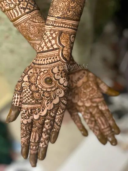 A close-up shot of a detailed party mehendi design. The focus is on the intricate patterns covering the palms and fingers.