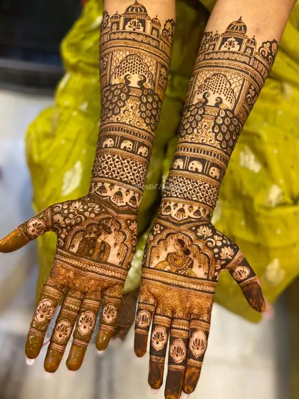 This bridal design features bride and groom figures on the palms, surrounded by peacocks and elephants. The top of the arms is adorned with palace-like architecture, completing the royal look.