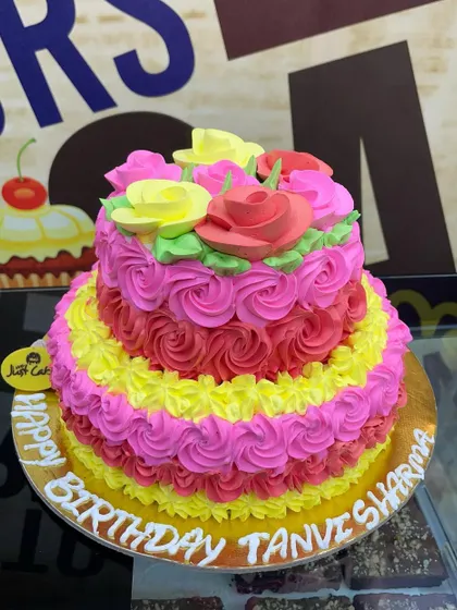 A vibrant 2kg two-tiered cake with bright pink and yellow rosette piping.
