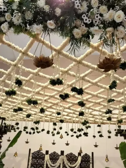 A detailed look at the hanging elements from the floral ceiling, including lotus-shaped holders and delicate flower strings, which add texture and depth to the overall mandap design.