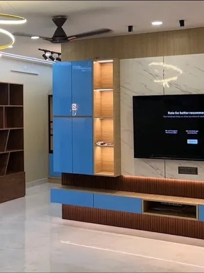 This living room features a bold TV unit with bright blue high-gloss cabinets, a marble-finish back panel, and a fluted wood base. The design is a perfect example of how to use color to create a vibrant and modern focal point.